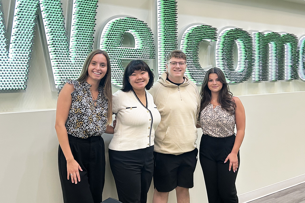 Students posing for a photo in front of a “Welcome” sign at Huntington Bank headquarters.
