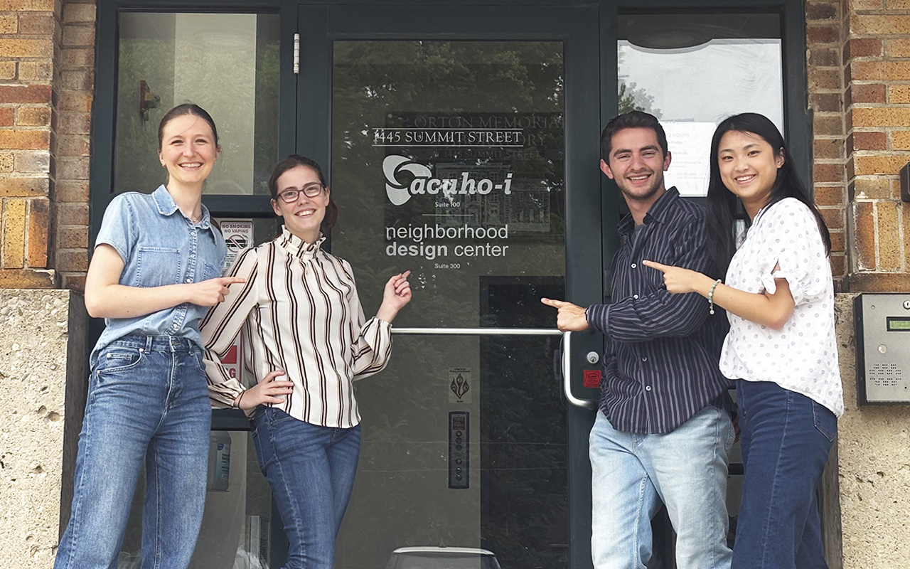 Students posing for a photo in front of an exterior office building door.