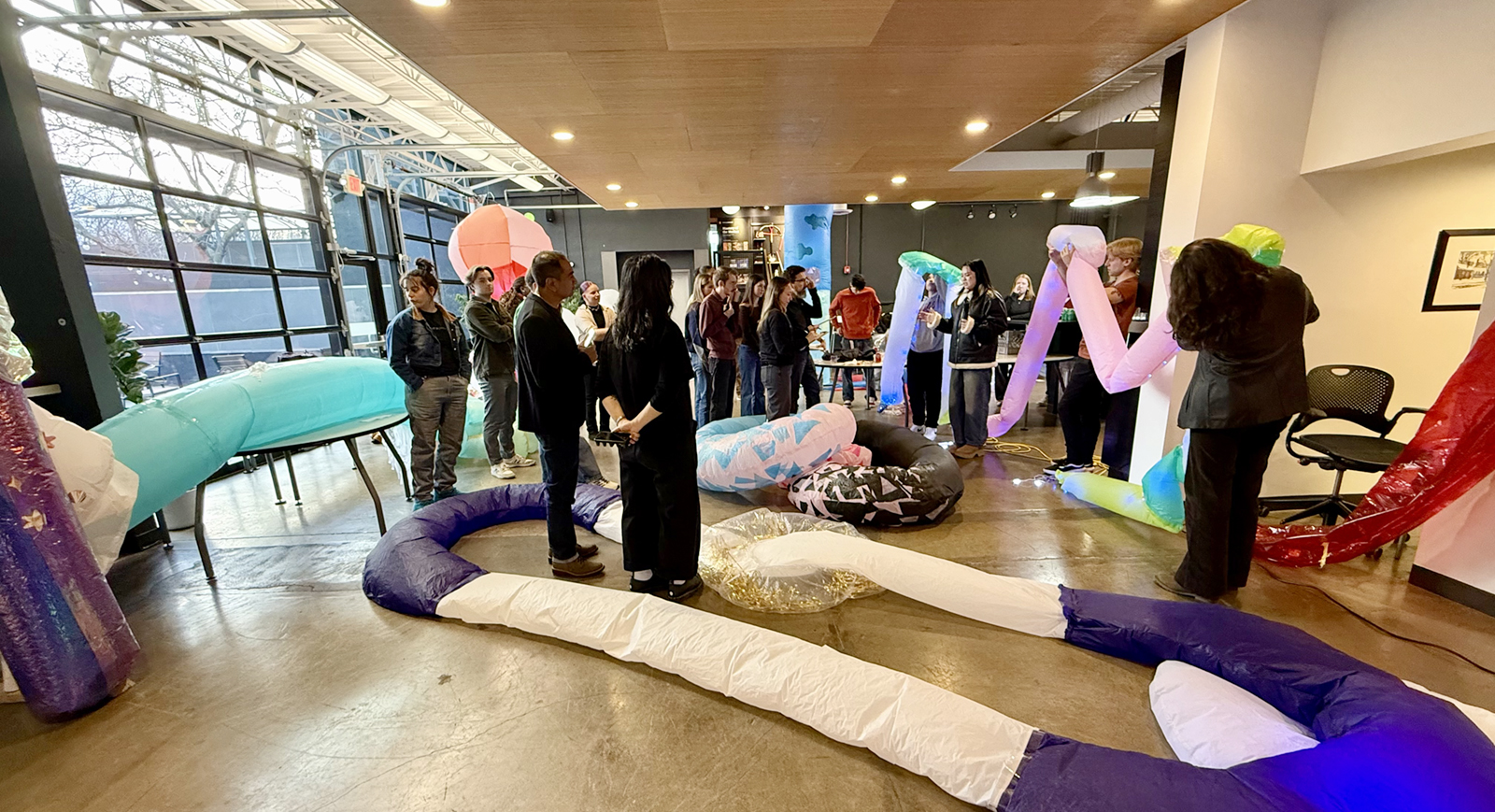Interior of office kitchen space filled with people and inflated objects.