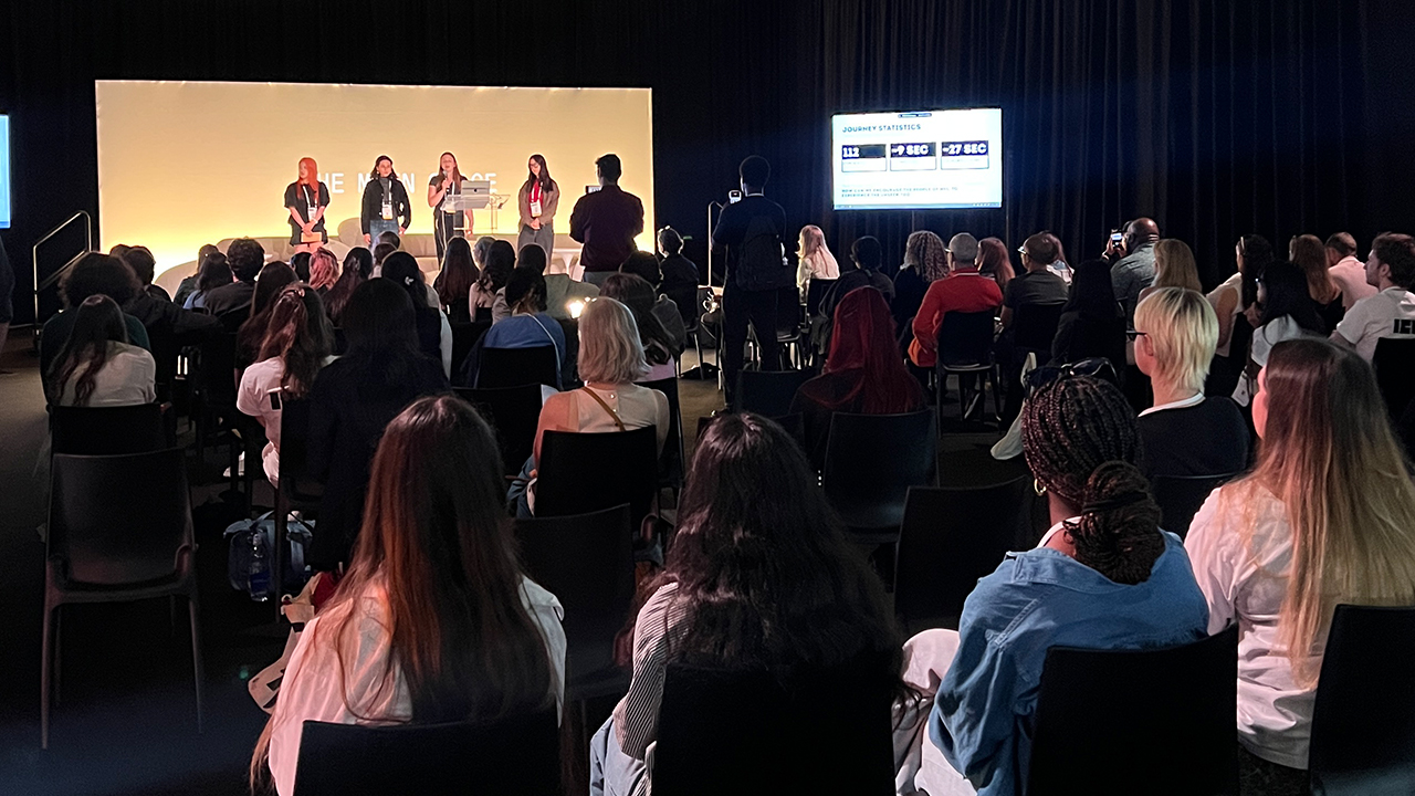A student group presenting their work on stage in front of an audience. 