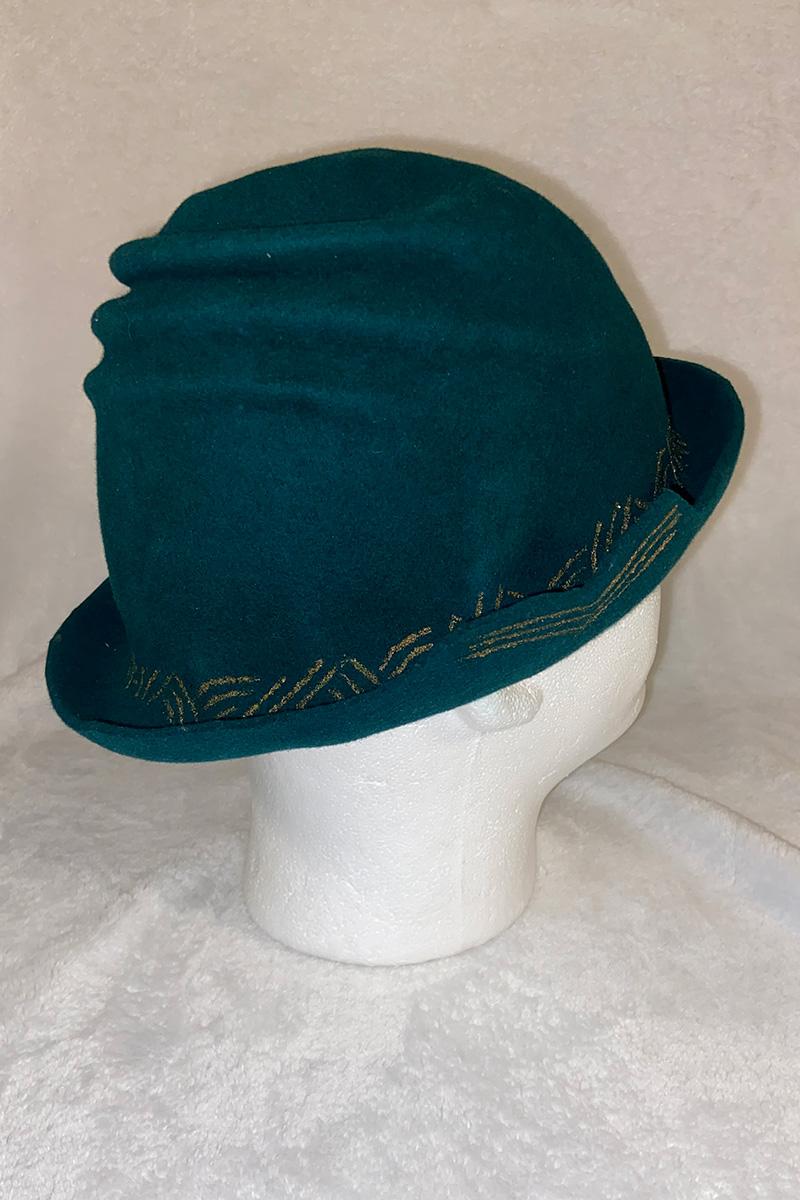 A green felt hat on a model head. The hat has a folded shape and a painted pattern reminiscent of book pages.