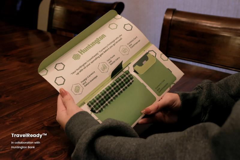 A student’s hands holding the TravelReady™ Currency Package above a kitchen table.