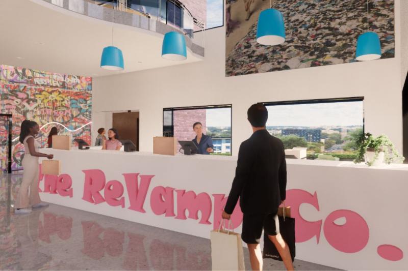 View of the checkout area on the right side of the first floor. This view showcases the checkout desk, with workers and people checking out. The name of the store is also featured on the desk. Different artwork, the elevator, and the overlook on the second floor can be seen in the background. Blue lights are shown over the desk, and two big windows are seen behind it