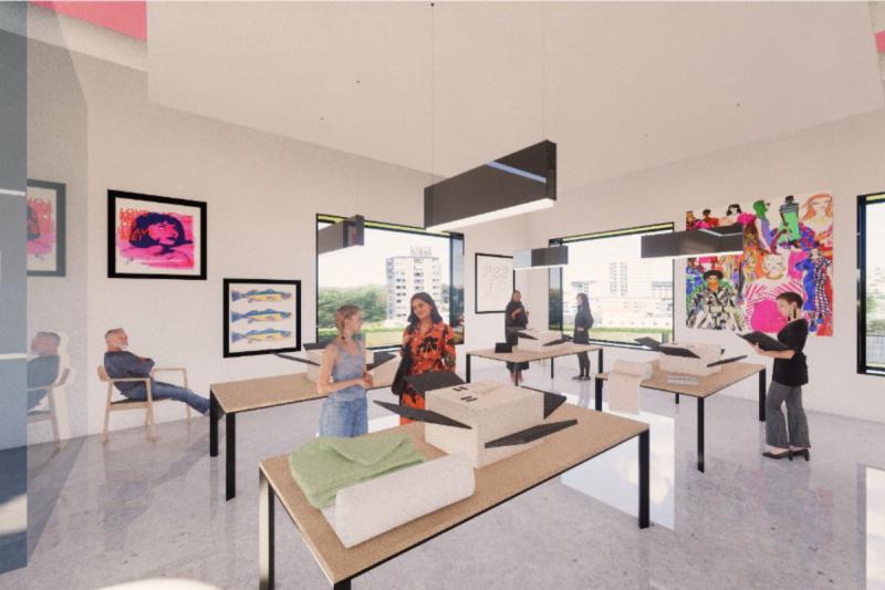 View of the screen-printing room, located on the back left side of the second floor. This view features tables with the screen-printing machines on them, some tables also have fabric on them. People are shown around the tables as well. Small design details show screen-printed artwork in the back. Two big windows are also shown, along with light fixtures in the front and back. A glass wall is also shown on the far left, which separates this room from the main staircase