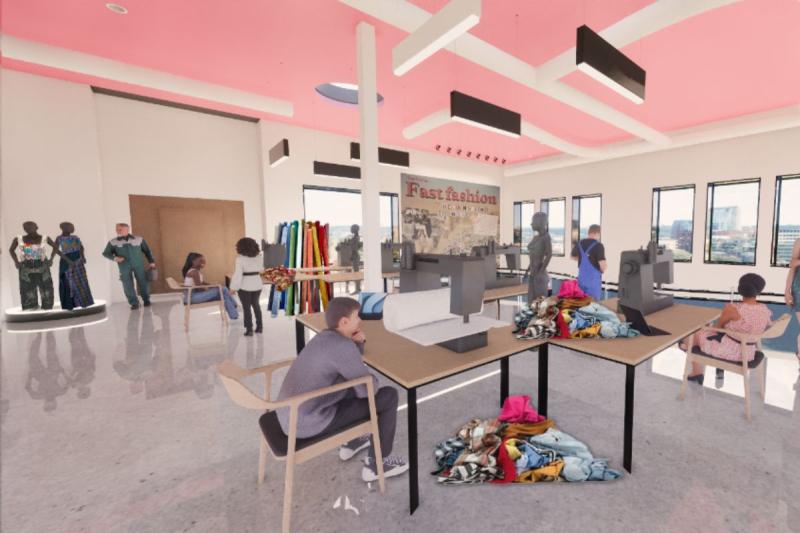 View of the sewing room on the second floor, beside the overlook. This view features desks with sewing machines, people working at the machines, and different fabrics scattered around. The elevator is also seen in the back of the rendering. This view also features windows, artwork, and light fixtures in the background