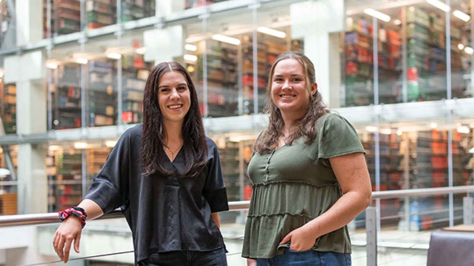 Portrait of Erika Strazinsky and Grace Gerber standing in front of bookshelves in Thompson Library.
