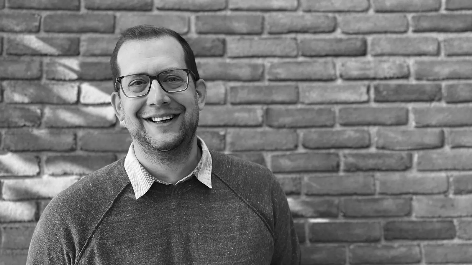 Black-and-white photo of Adam Fromme in front of a brick wall.