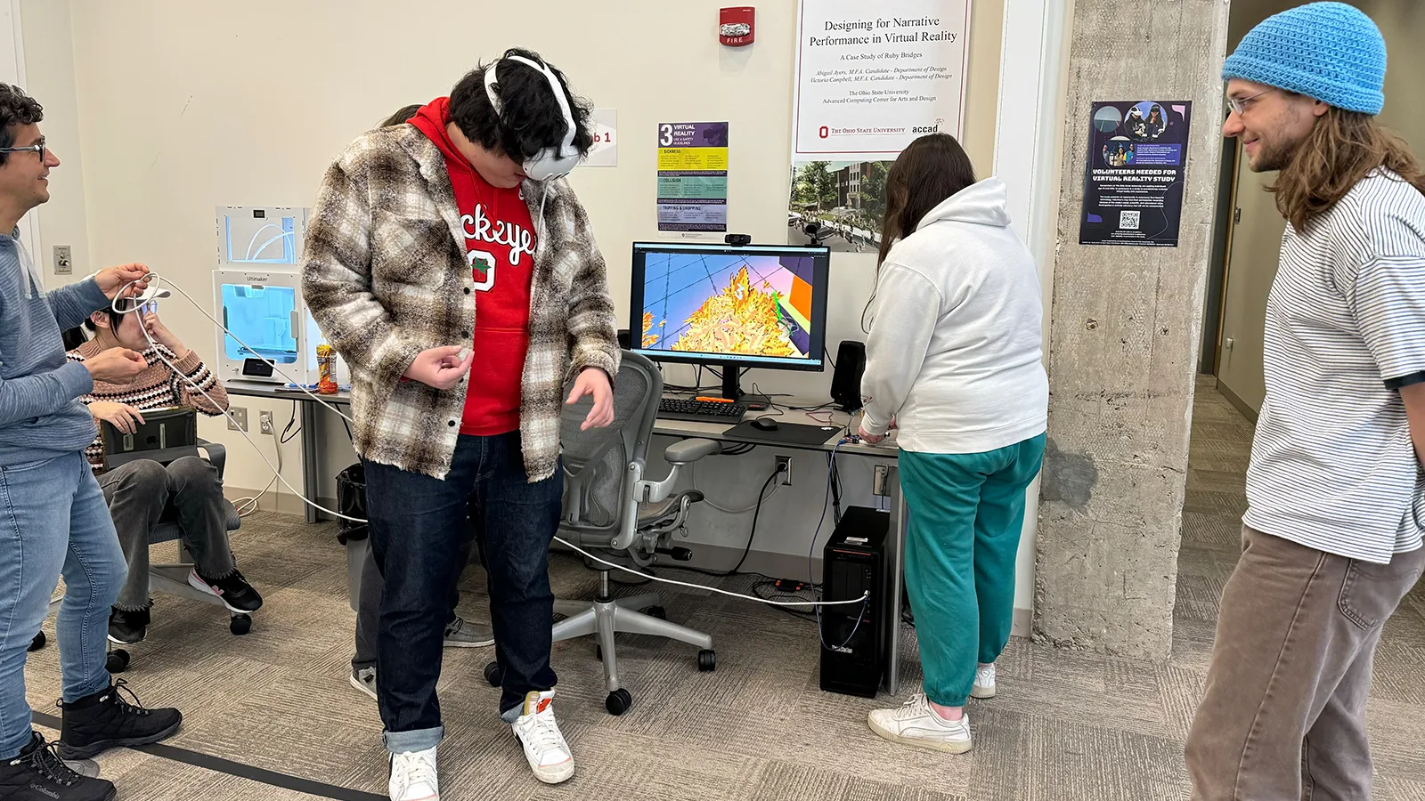 Four students watching one student test a VR application while wearing a headset.