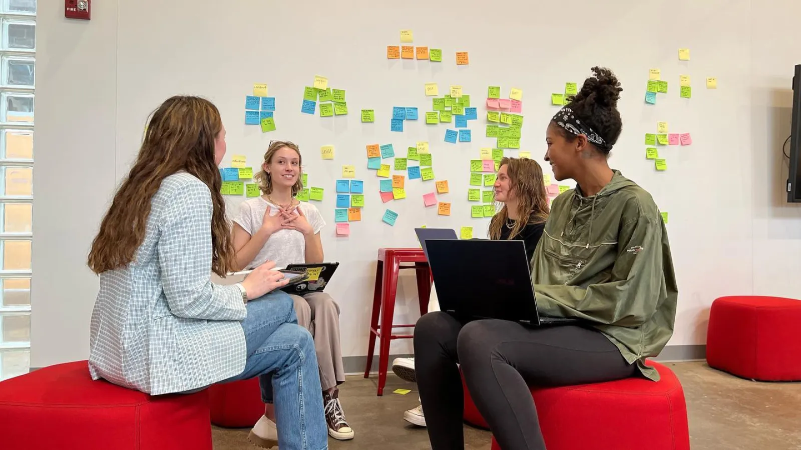 students collaborating in front of a wall with brainstorming post-it notes.