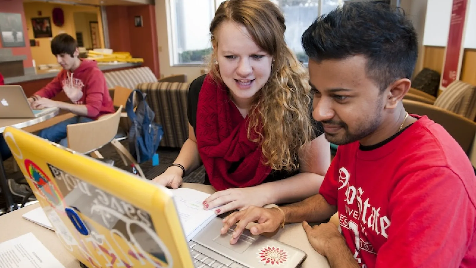 Staff member collaborating with a student on a laptop. 
