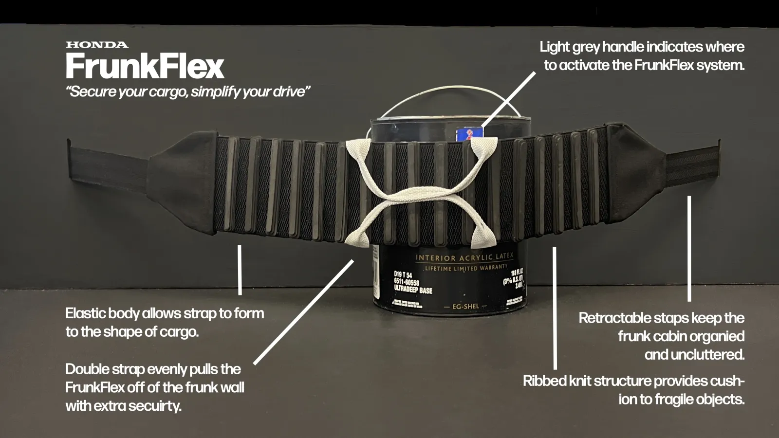 A product prototype labeled "FrunkFlex" is displayed against a black background. The device is a flexible cargo-securing strap with ribbed knit padding, stretched around a paint can to demonstrate its functionality. White text annotations highlight key features, including an elastic body that conforms to cargo, a retractable strap system for organization, and a double strap for extra security. The light gray handle marks the activation point for the system.