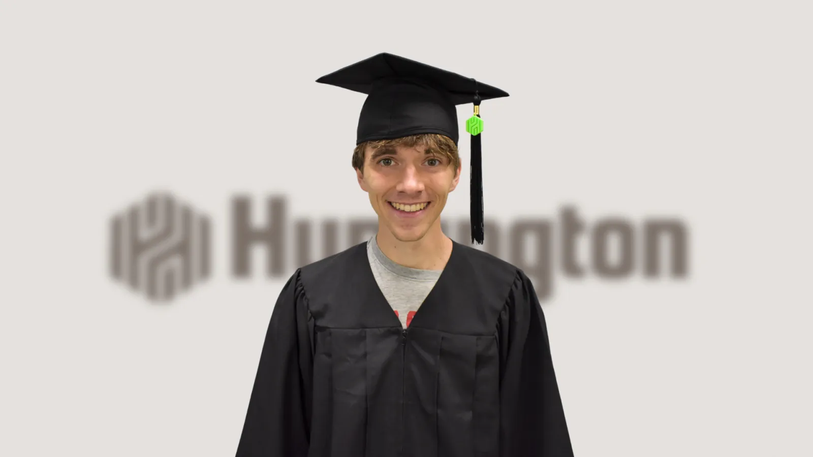 5.	An image of a Cross Country athlete at The Ohio State University wearing a graduation cap and gown with a Huntington branded tassel. In the background is the Huntington logo blurred out. 