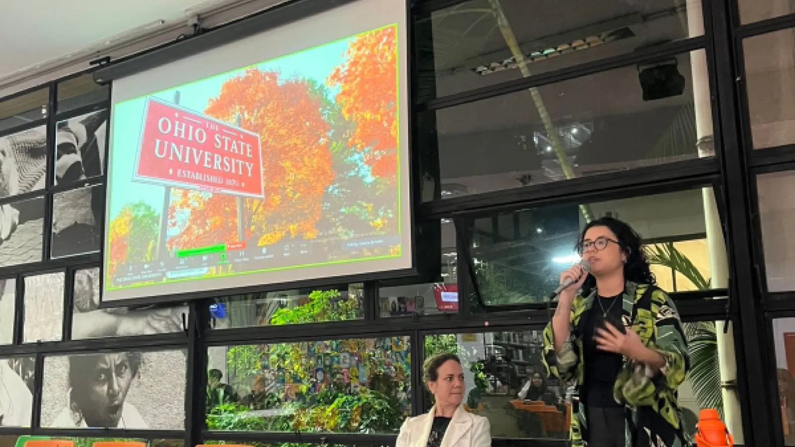 Barbara speaks with a microphone in front of a screen with the Ohio State University sign