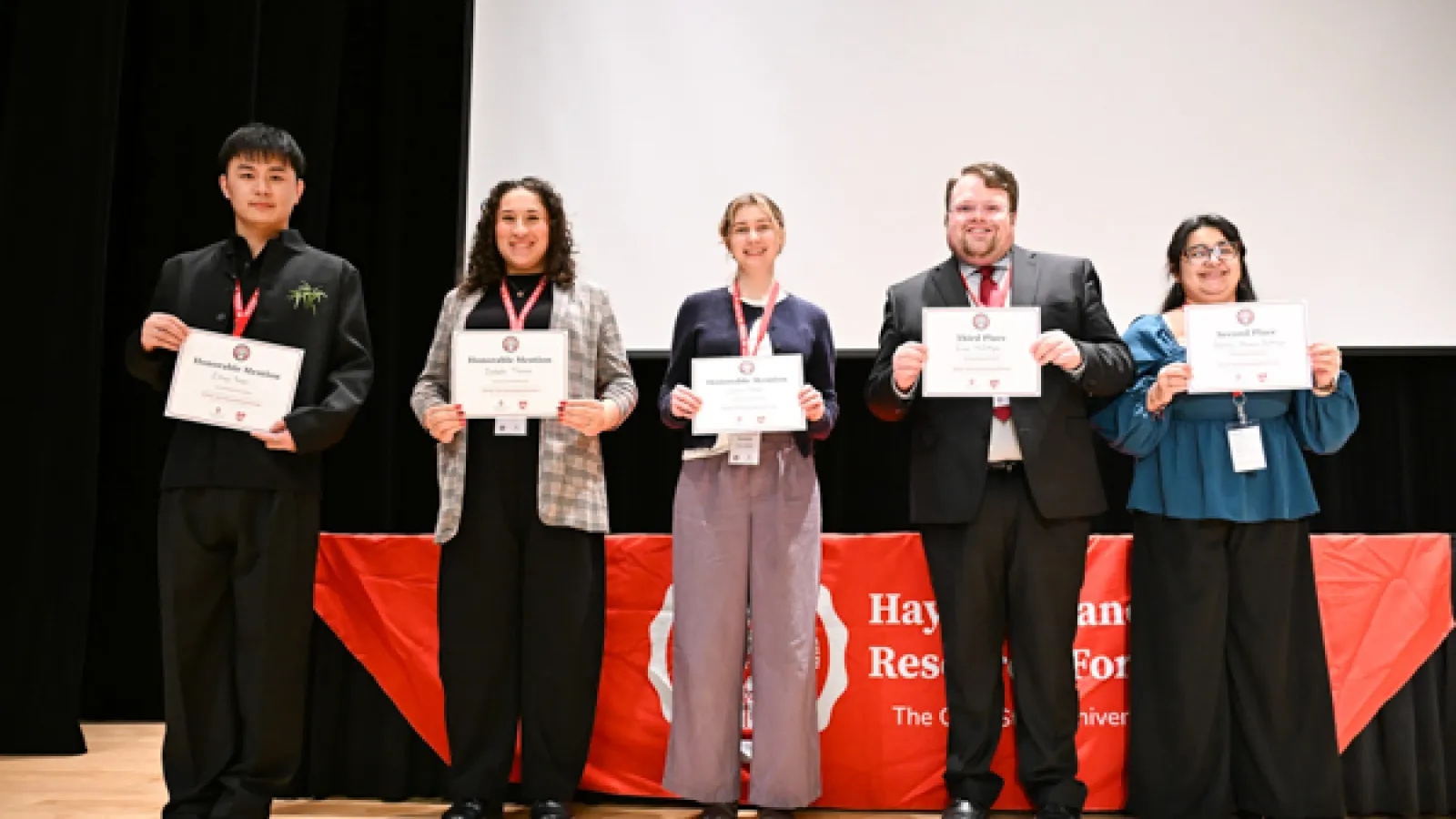5 students stand holding award certificates