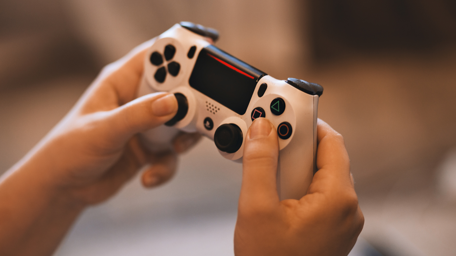 Two hands holding a gaming console controller. 
