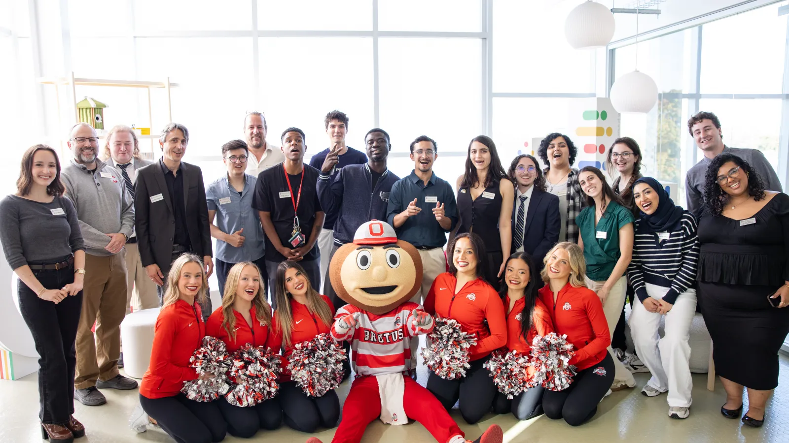 A large group of students, faculty posing with the OSU cheer squad with Brutus Buckeye.