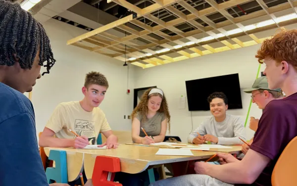 Students gathered around a table collaborating on a design project.