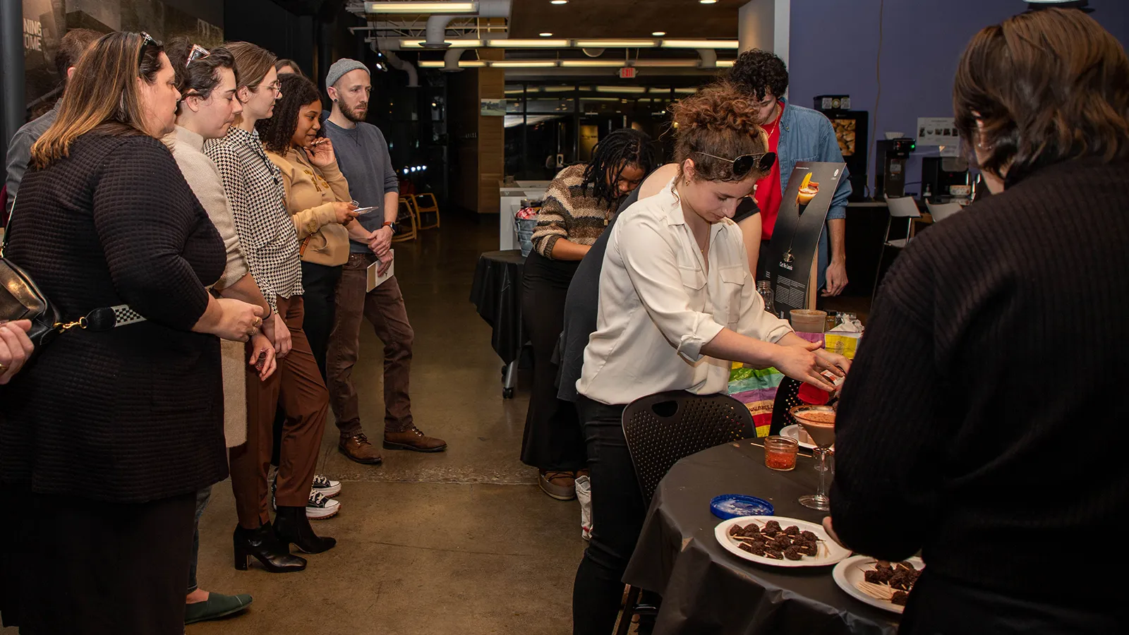 A group of judges watch as students prepare a mocktail drink.