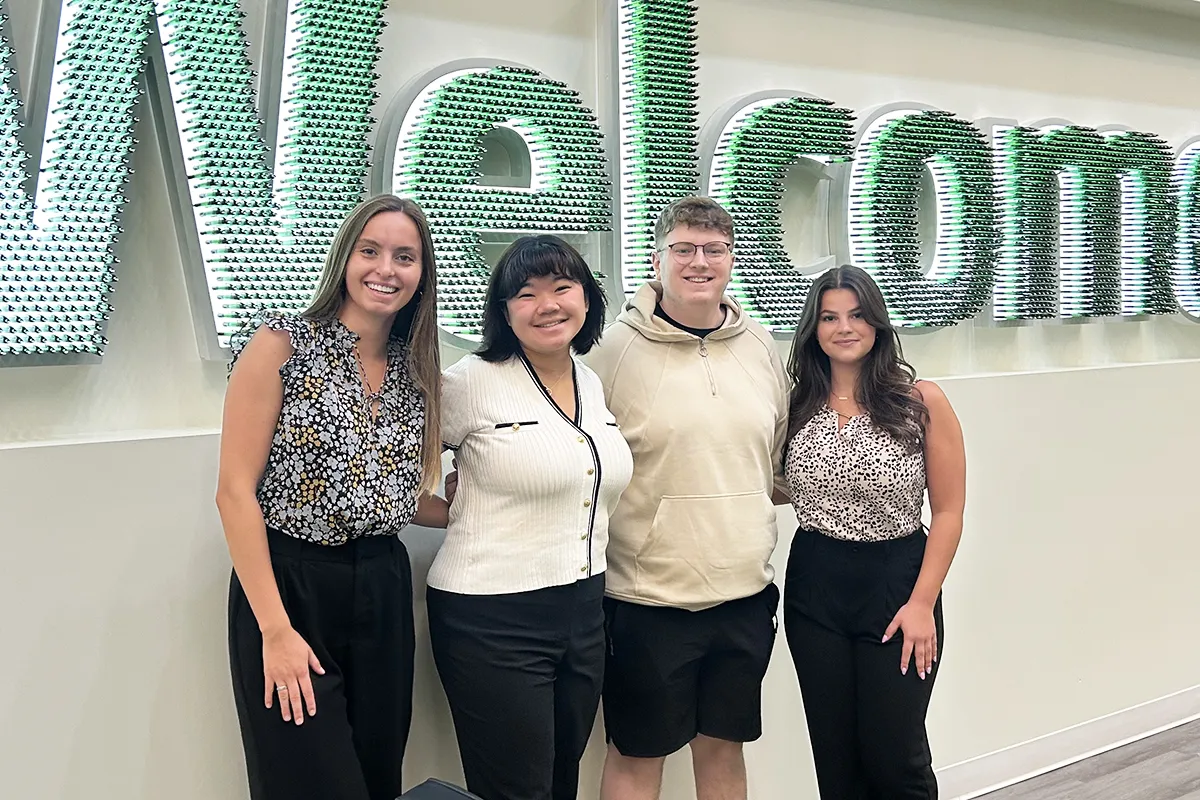 Students posing for a photo in front of a “Welcome” sign at Huntington Bank headquarters.