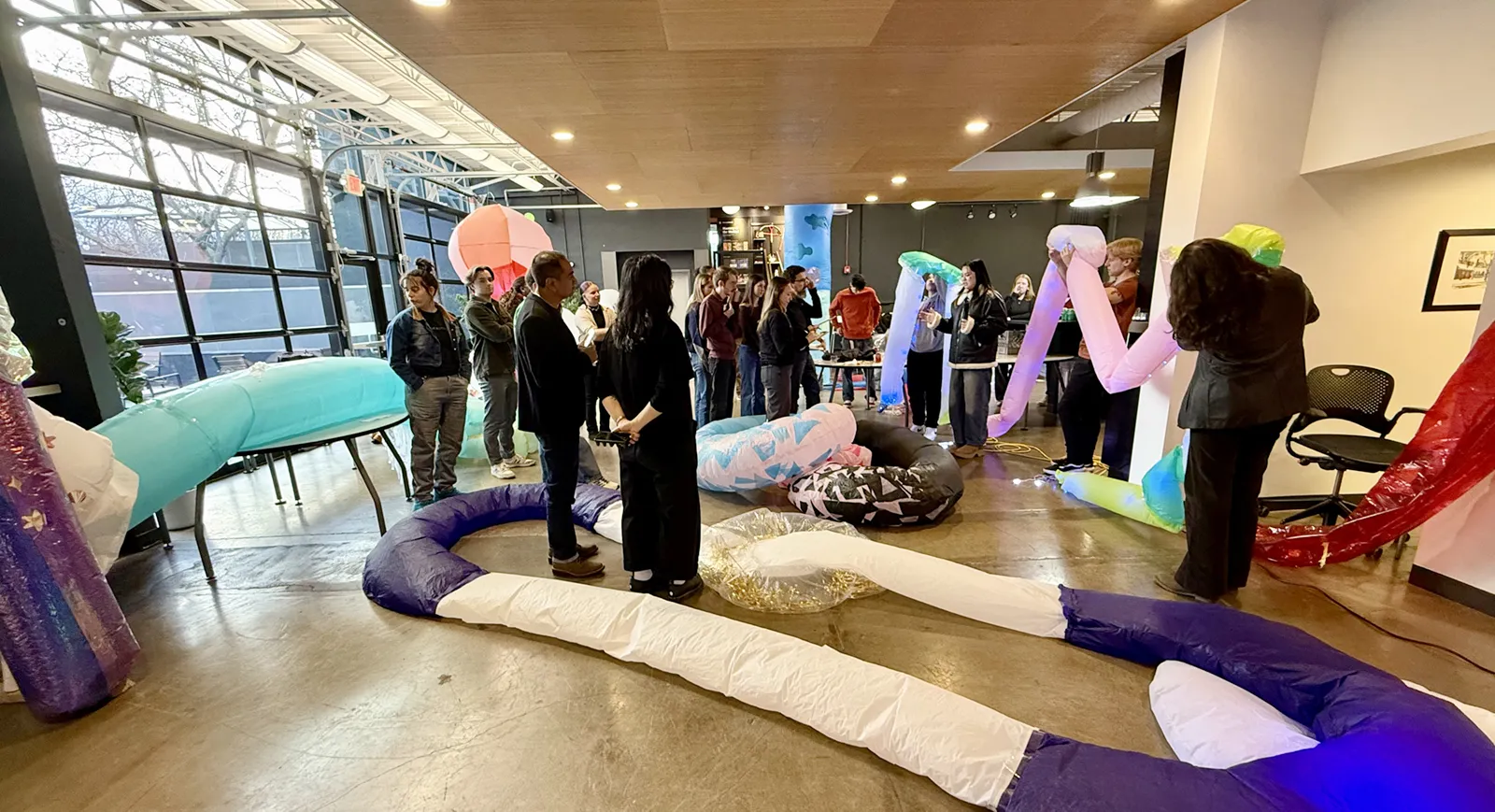 Interior of office kitchen space filled with people and inflated objects.
