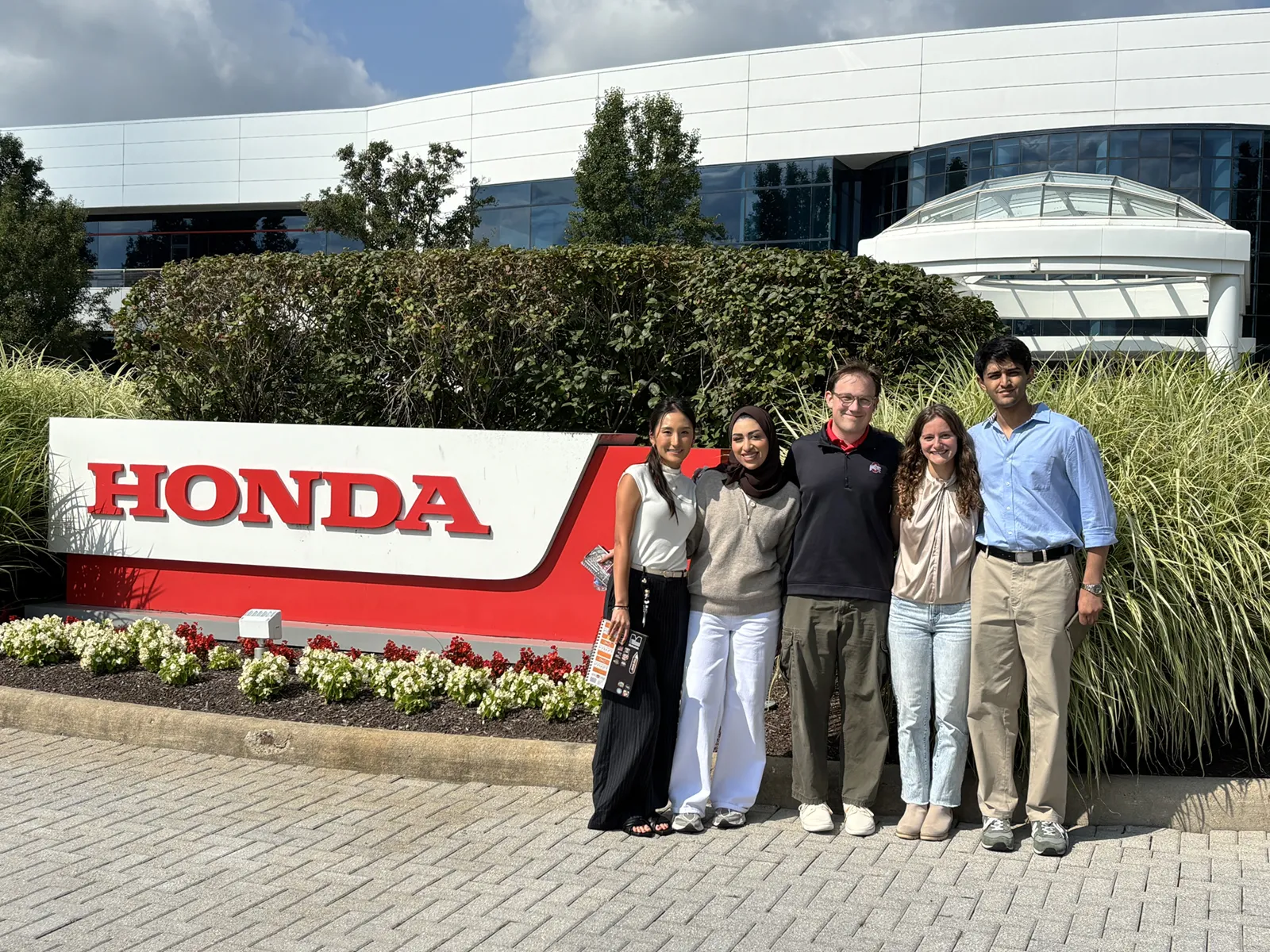 Students posing for a photo in front of Honda sign.