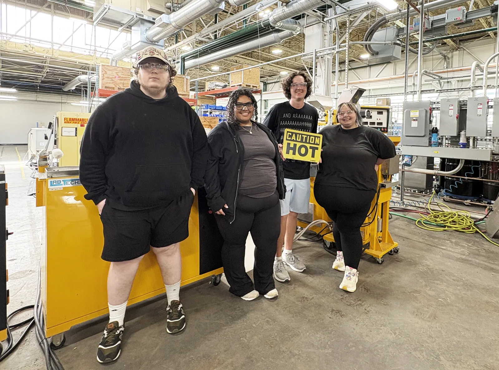 Students posing for a photo on a factory floor.