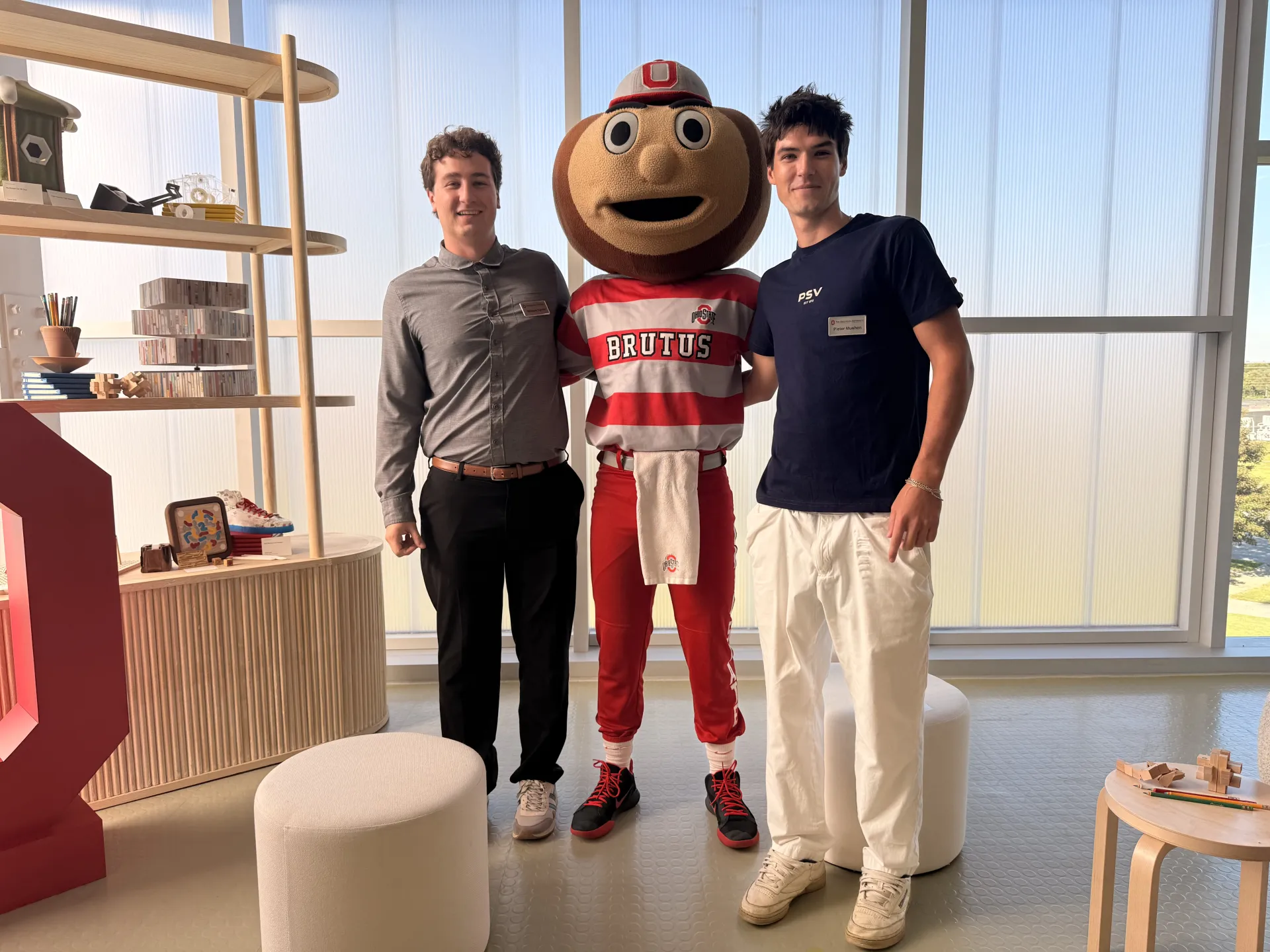 Two design students posing with Brutus the Buckeye in the center. 