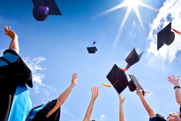 Stock image of student through graduation caps into air.
