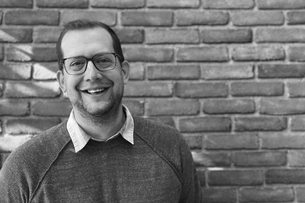 Black-and-white photo of Adam Fromme in front of a brick wall.