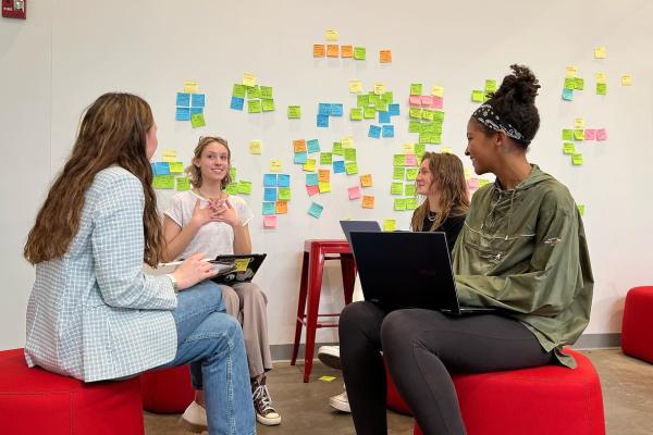 students collaborating in front of a wall with brainstorming post-it notes.