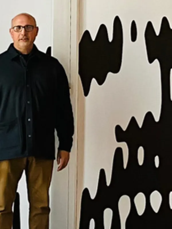 Paul Nini standing in front of the Peter Megert Exhibit, Hopkins Hall gallery.