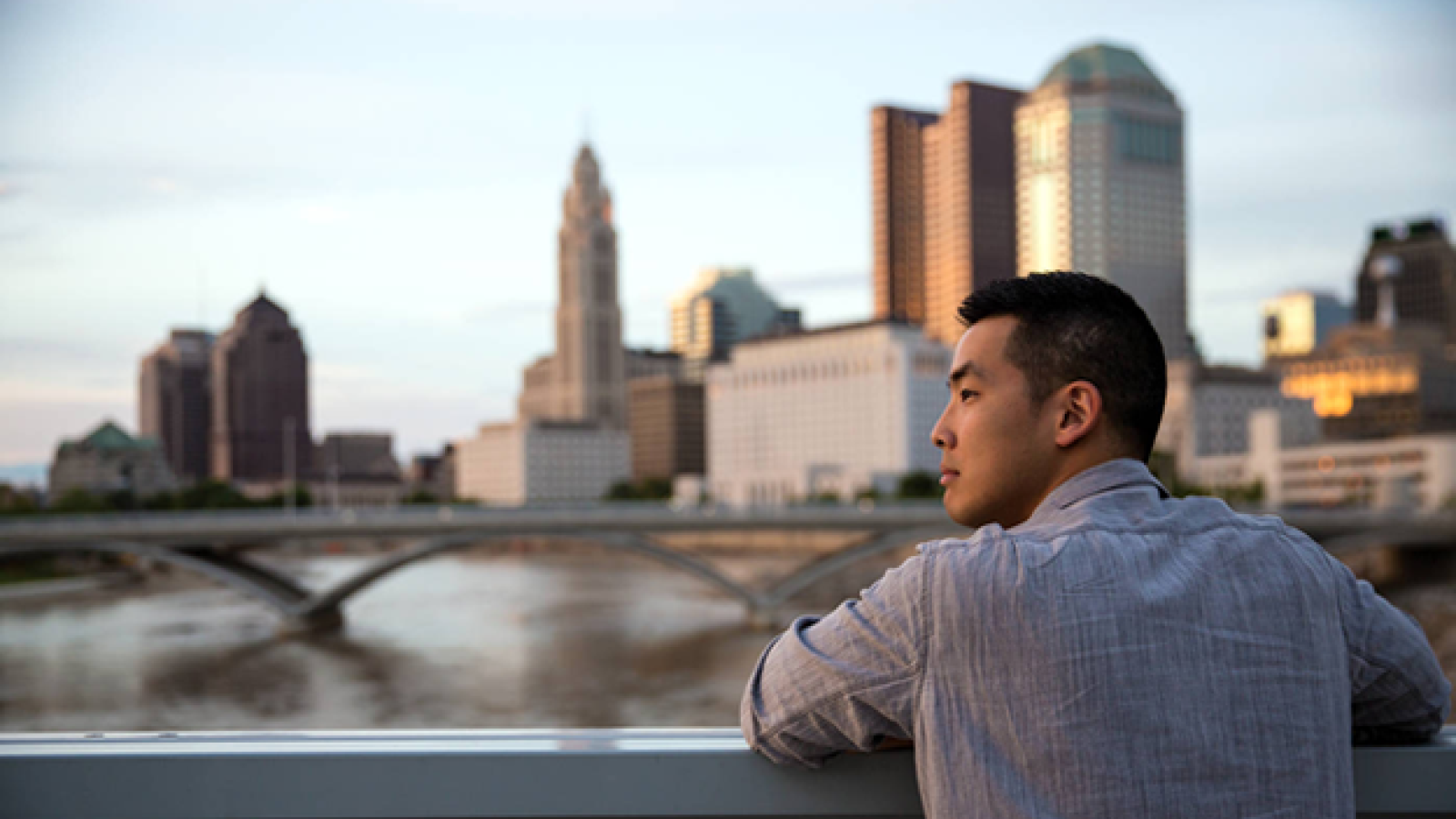 person gazing at river with downtown Columbus skyline in the background