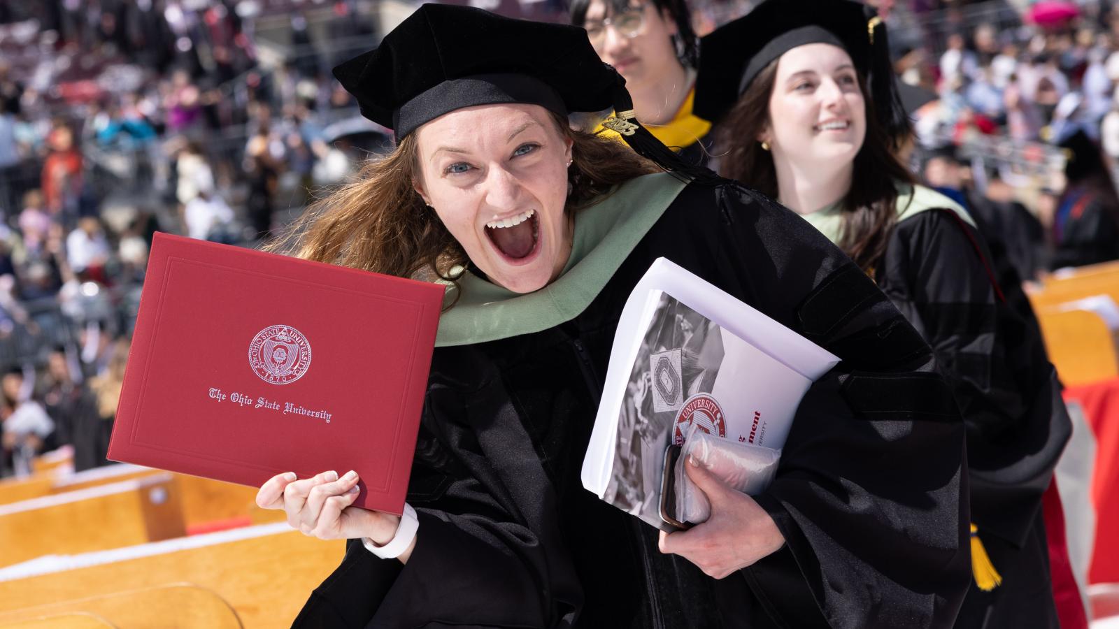 Happy graduates with diplomas. 2023 spring commencement in Ohio Stadium.