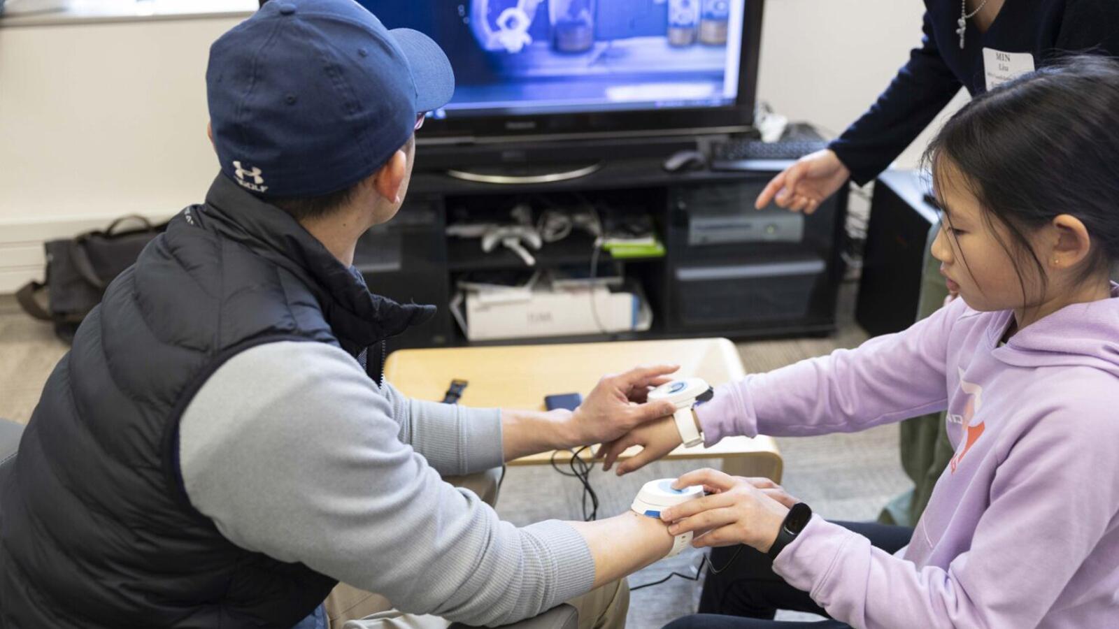 Two people testing a touch user interface attached to their wrists.