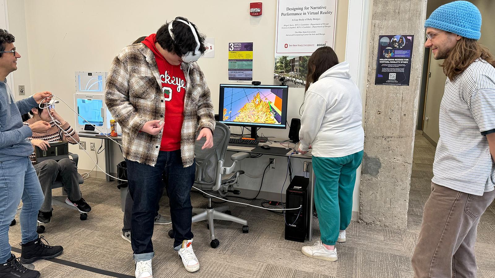 Four students watching one student test a VR application while wearing a headset.