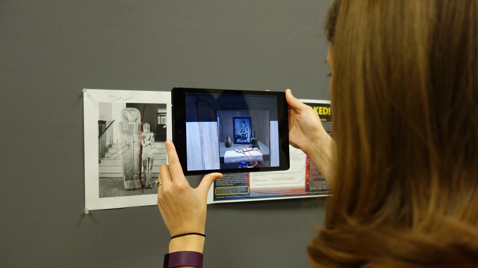Over the shoulder view of a person holding an iPad to view AR.