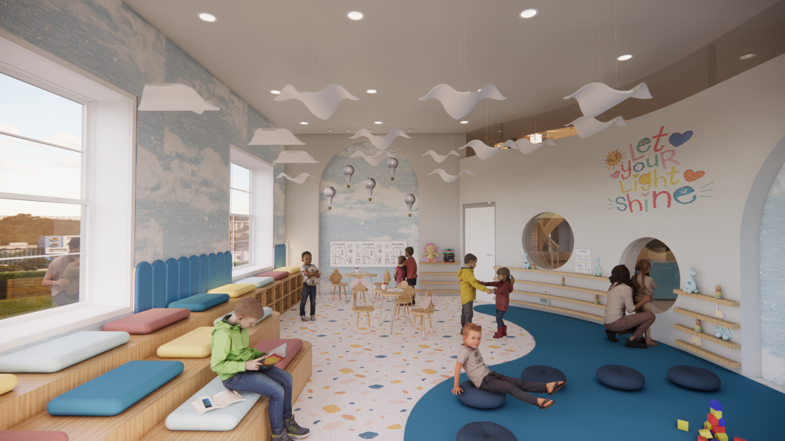 A vibrant and modern children's learning space featuring a sky-themed design with cloud-shaped hanging lights, a soft blue and white color palette, and a mural with floating hot air balloons. The walls are adorned with playful elements, including a colorful message that reads "Let your light shine." There are various seating options, including tiered wooden benches with colorful cushions, a curved reading nook with blue floor mats, and small wooden tables with child-sized chairs. Shelving along the wall dis