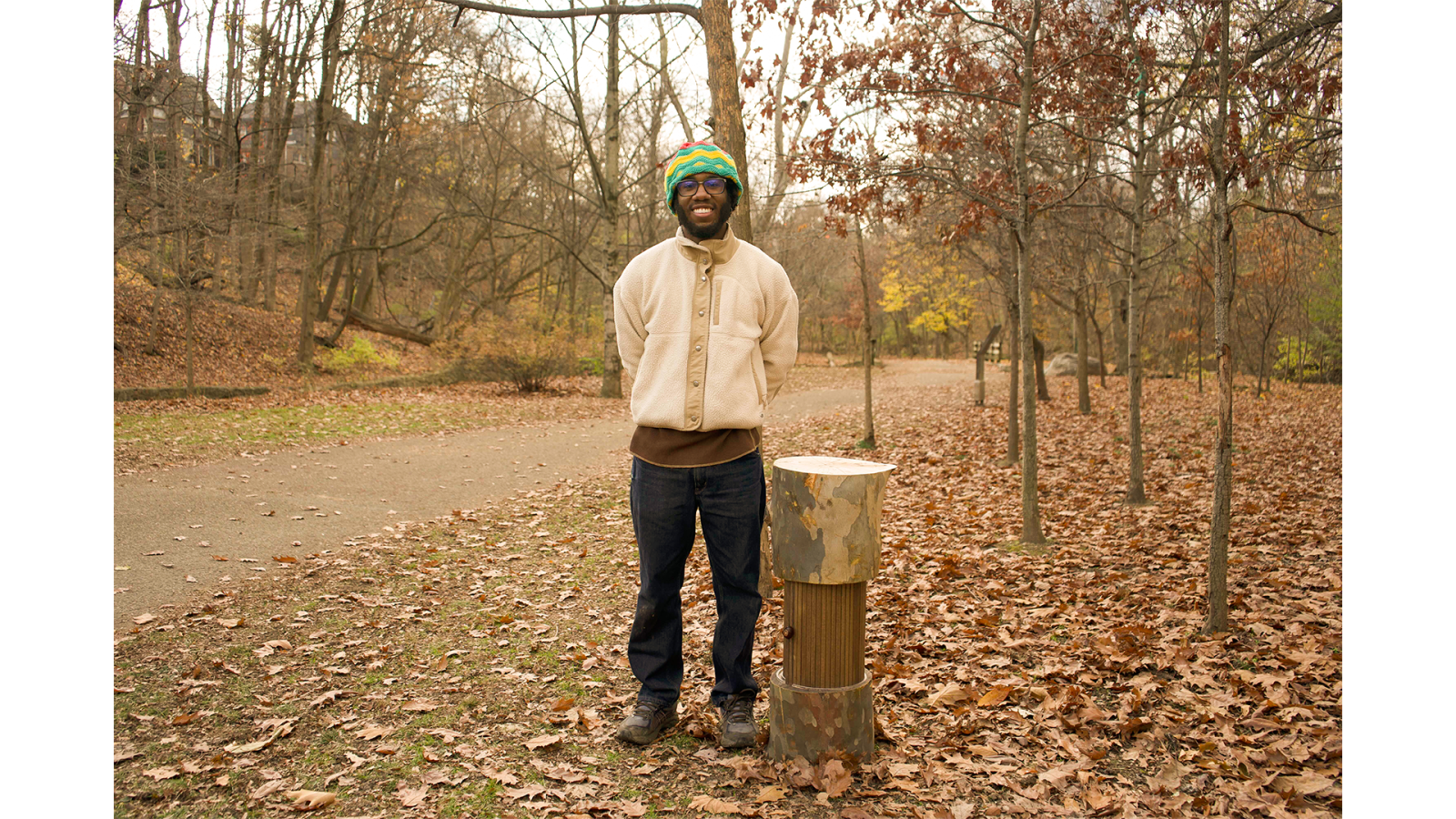 A person poses next to the tree-stump-inspired Heritage Ring, smiling.